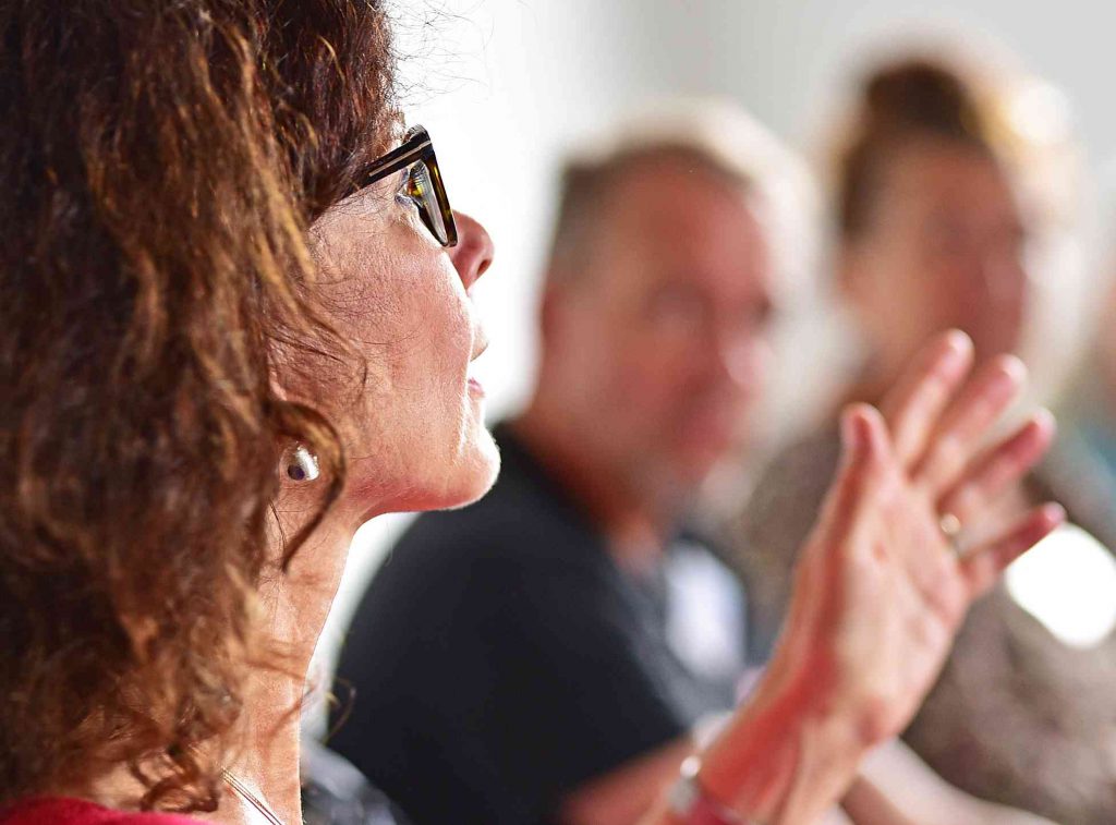 Frau von der Seite, spricht vor Gruppe und gestikuliert mit den Händen in der Einführung Positive Psychologie